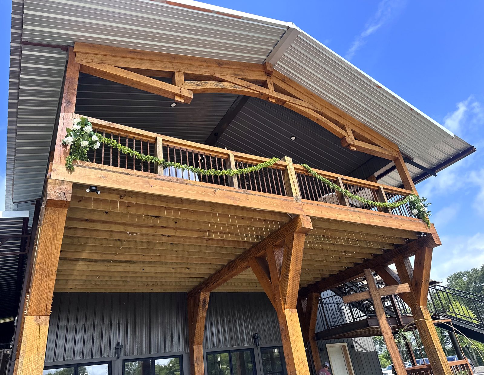 Timber-framed balcony with greenery garland against a blue sky